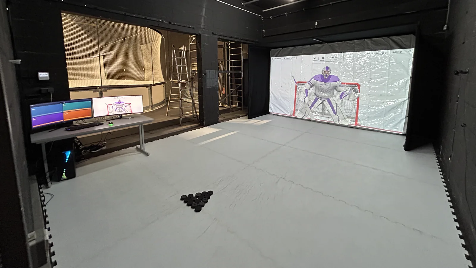 A SnipeZone room at an arena — operator station, projected goalie and pucks on the floor